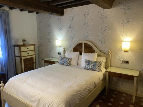 埃尔瓦Apartamentos Rurales El Zarzo的一间卧室配有白色床单和蓝色壁纸。