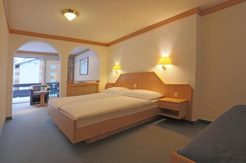 萨斯费阿尔宾高级酒店的一间卧室配有一张大床和两盏灯