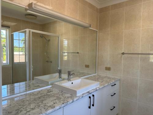 汤斯维尔Townsville Wistaria Spacious Home的一间带水槽、淋浴和镜子的浴室