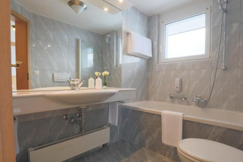 萨斯费阿尔宾高级酒店的浴室配有盥洗盆、卫生间和浴缸。
