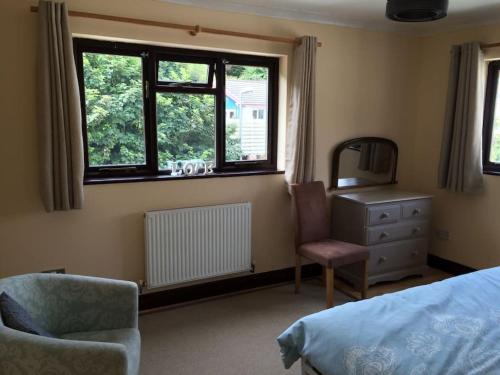 波斯陶恩Brook beach retreat, Porthtowan, Cornwall的卧室配有床、椅子和窗户。