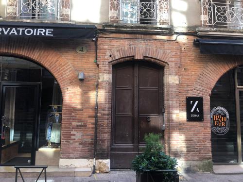 图卢兹Appartement de prestige – rue des Arts的砖砌的建筑,上面有大棕色的门