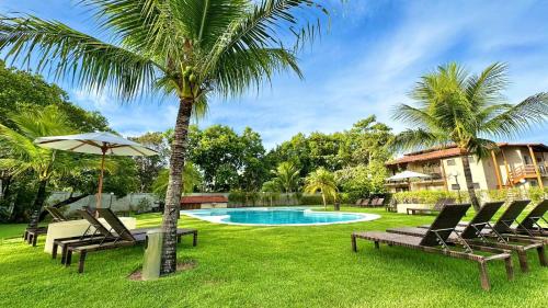 塞古罗港Apartamento na Vila La Torre的一个带椅子的游泳池、棕榈树和房子