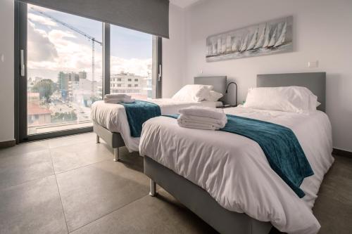 拉纳卡Gaia Seaview Apartment 1的带大窗户的客房内的两张床