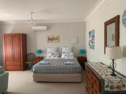 CarramarBentworth Lodge的一间卧室配有一张床和一张带台灯的桌子