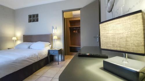 莫桑莱阿尔皮莱Hôtel Les Magnanarelles的一间卧室配有一张床和一张带电脑显示器的书桌