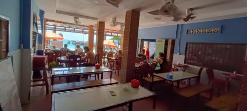 瓜隆岛Family Guesthouse的一间设有桌椅的餐厅,里面有人