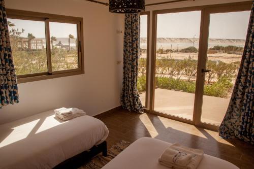 达赫拉Dakhla Camp的一间卧室设有一张床和一个享有海滩美景的窗户。
