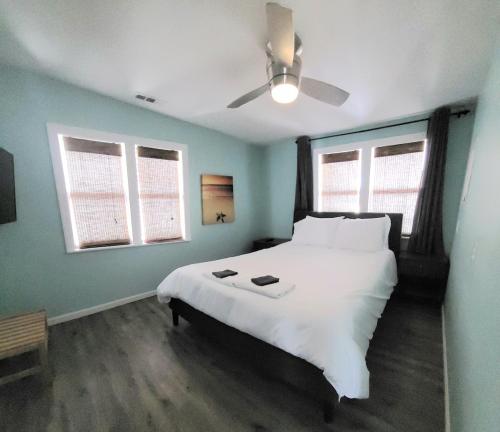 卡罗来纳比奇Beachwood Bungalow A的卧室配有一张白色大床和吊扇