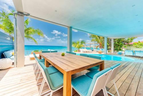 马霍礁Surfsong Villa- Luxury Water Front Villa for 12的一间带桌椅的用餐室和一个游泳池