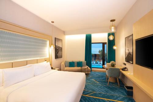 马斯喀特Maani Muscat Hotel & Suites的酒店客房配有一张床、一张书桌和一台电视。