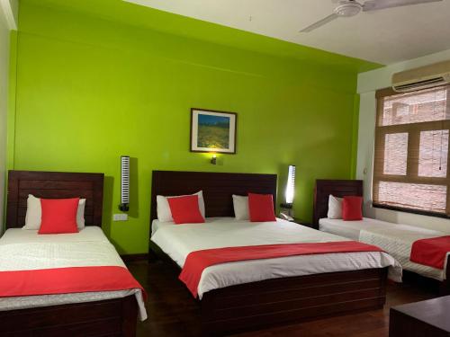 贾夫纳Subhas Tourist Hotel的绿色客房的两张床,拥有绿色的墙壁