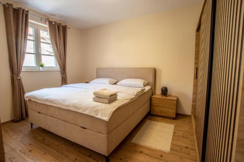 伦达瓦Landena Apartments Lendava的一间卧室配有一张带白色床单的床和一扇窗户。