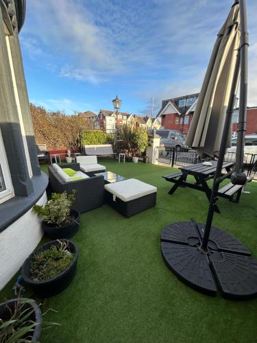布莱克浦北魁斯特酒店的庭院配有遮阳伞和桌椅。