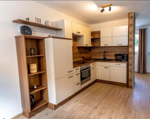 伦达瓦Landena Apartments Lendava的厨房铺有木地板,配有白色橱柜。