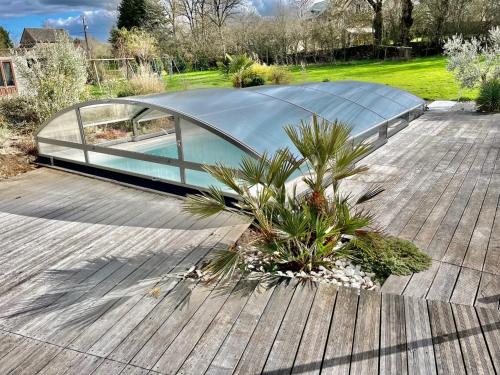 奥内莱沙托Villa contemporaine avec piscine sur 4000 m2 à Rodez 9 personnes的木甲板上的玻璃房子,种植了植物