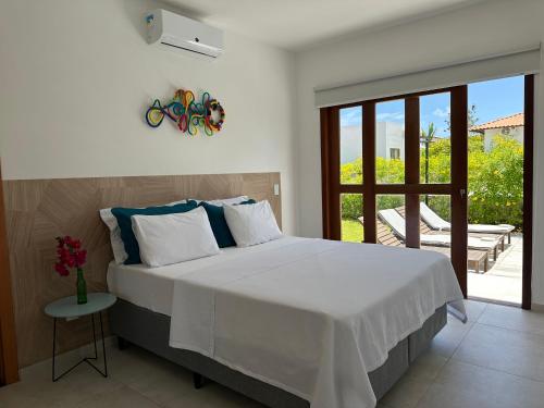 皮帕Casa Ibiza - Pipa ''Luxurious 3-Bedroom Villa with pool''的一间带一张白色大床的卧室和一个阳台