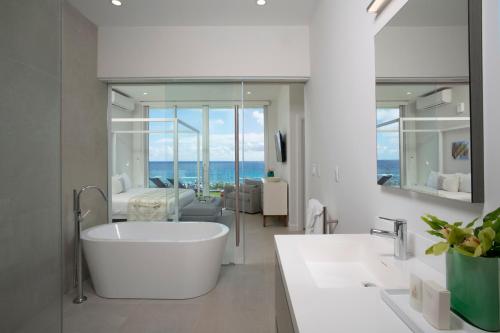 百慕大Azura Bermuda的带浴缸的白色浴室和客厅。