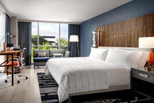 Avon ParkLe Méridien Dania Beach at Fort Lauderdale Airport的酒店客房设有一张大床和一张书桌。