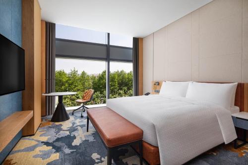 上海上海嘉定福朋喜來登酒店的一间卧室设有一张床和一个大窗户
