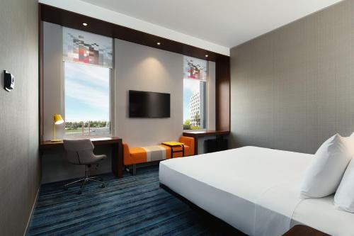 迪拜Aloft Dubai South的酒店客房设有一张床、一张书桌和一台电视机。