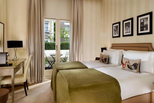 伦敦森雅酒店 - 签名收藏的一间卧室配有一张床、一张书桌和一个窗户。