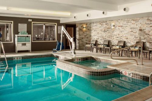 沃特伯里Fairfield by Marriott Waterbury Stowe的游泳池位于酒店房间,周围设有椅子