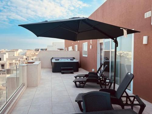 比尔基卡拉The Hazel penthouse with private jacuzzi的阳台的天井配有椅子和遮阳伞。