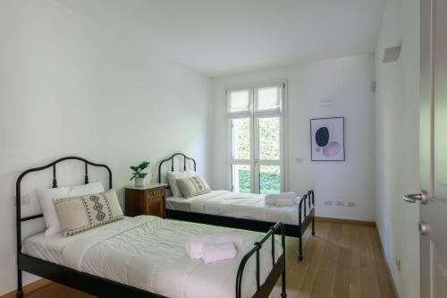 格里安泰卡德纳比亚Casa Divina - Cadenabbia的配有2张床的白色墙壁和窗户。