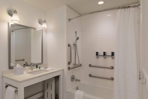 西塔科西雅图机场南福朋喜来登酒店的白色的浴室设有水槽和淋浴。