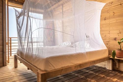 GuachacaMendihuaca Surf Camp的配有蚊帐的木制客房内的一张床位