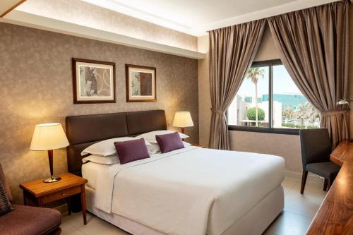 利雅德利雅得喜来登酒店的卧室设有一张白色大床和一扇窗户。