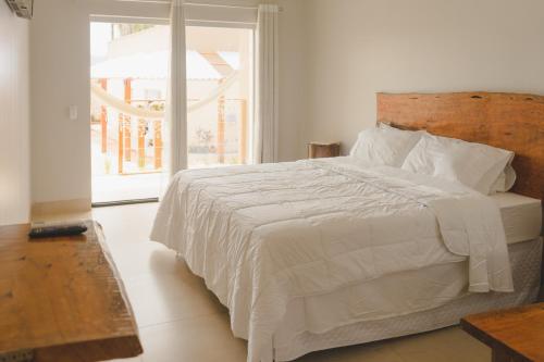 戈亚斯州上帕莱索Pousada Paraiso的卧室配有白色的床和大窗户