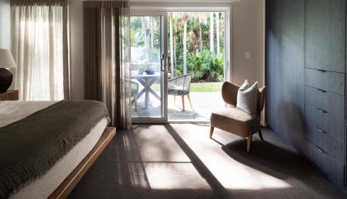 麦夸里港Tallowwood House Luxury Bed & Breakfast的一间卧室配有一张床、一把椅子和滑动玻璃门