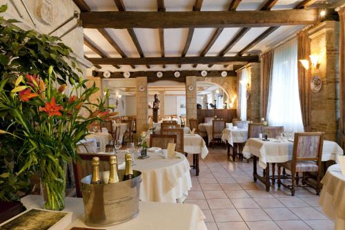 圣梅内乌勒Logis Le Cheval Rouge的一间设有白色桌椅和鲜花的餐厅