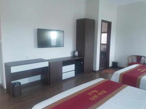 Làng ThànhKhách sạn Bảo Sơn Bắc Giang的一间卧室配有两张床和一张书桌及电视