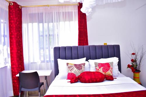 基苏木Rozy Penthouse的一间卧室配有一张带红色窗帘的床和一张桌子