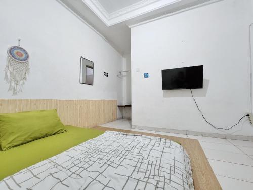 泗水Homey Guesthouse Kertajaya (Syariah)的一间设有床铺和墙上电视的房间