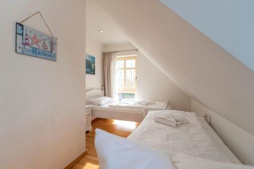 KarninFerienhaus Karnin B的白色的客房设有两张床和窗户。