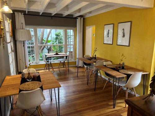 比勒陀利亚Battiss Guest House的一间带桌椅的用餐室和窗户。
