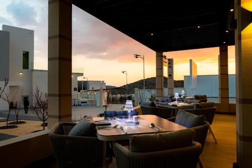 Jabal Al AkhdarDamask Resort的餐厅设有桌椅,享有日落美景。