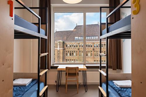 乌得勒支Stayokay Hostel Utrecht Centrum的客房设有双层床、桌子和窗户。