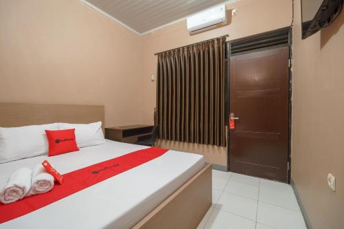 贝克西RedDoorz Syariah @ Bulak Kapal的一间卧室配有一张带红色枕头的床和一扇门