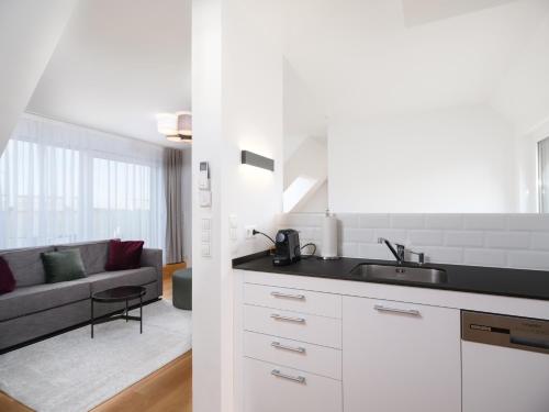 维也纳MyFavorit by Duschel Apartments Vienna的一间带水槽的白色厨房和一个客厅