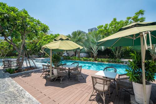 胡志明市Cozrum Homes - Sonata Residence的游泳池旁带桌子和遮阳伞的天井
