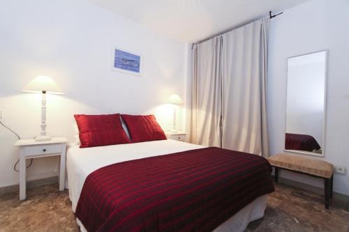 萨洛BAHIA II HomeStay by Turismar的一间卧室配有一张带红色枕头和镜子的床
