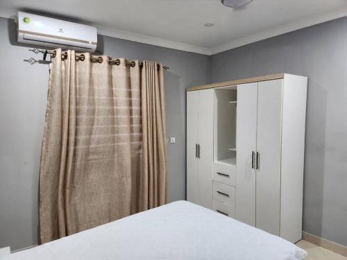 DawhwenyaSpacious Luxury 3Bed Hse in Tema - Netflix Wi-fi的一间卧室配有床、梳妆台和窗帘