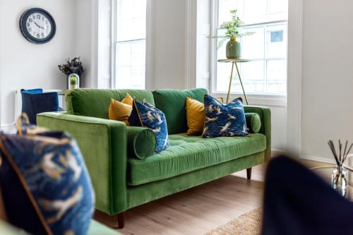 贝尔法斯特Wilton House Belfast Serviced Apartments的客厅里配有蓝色和黄色枕头的绿色沙发