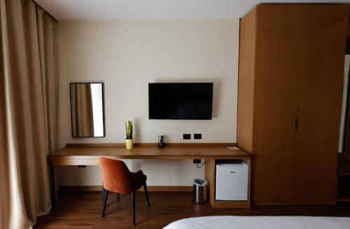 伏罗拉Valza Boutique Hotel的一间卧室配有一张桌子、一台电视和一把椅子