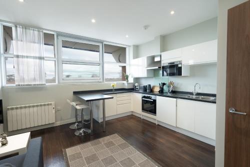 伦敦Superb Studio的厨房配有白色橱柜和黑色台面